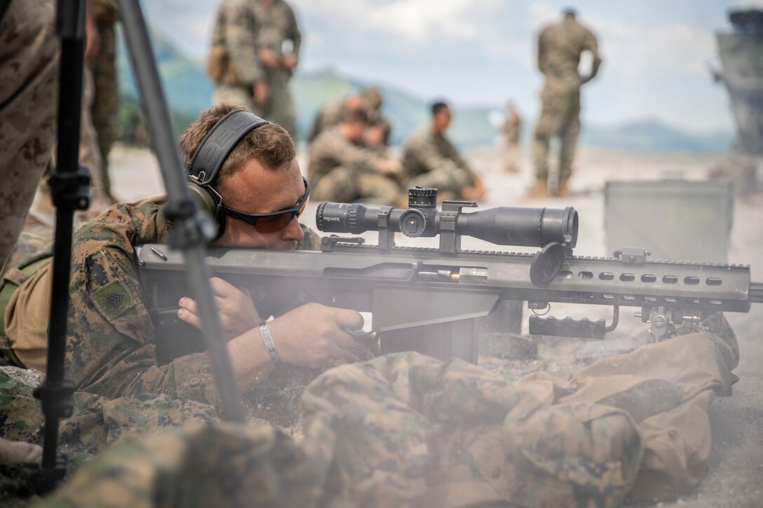 A Marine lies prone while preparing to fire a rifle.