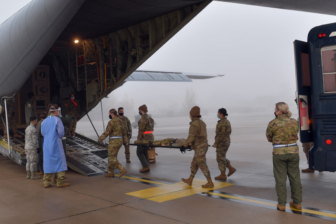 Airmen carrying a mannequin on a stretcher onto an aircraft.