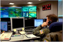 A photo of a North American Aerospace Defense Command and United States Northern Command operator answering the phone while on shift in the NORAD and USNORTHCOM command center.