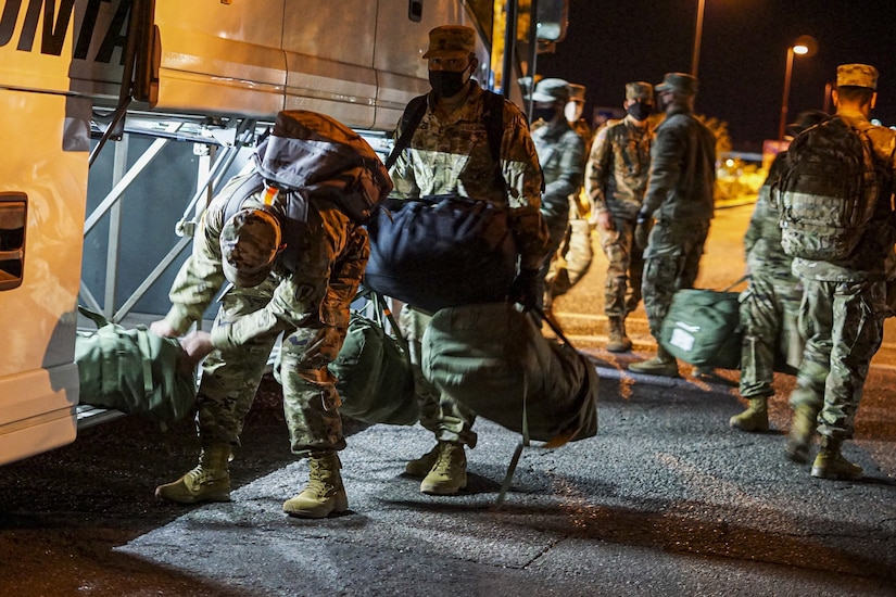 Soldiers unload a bus.