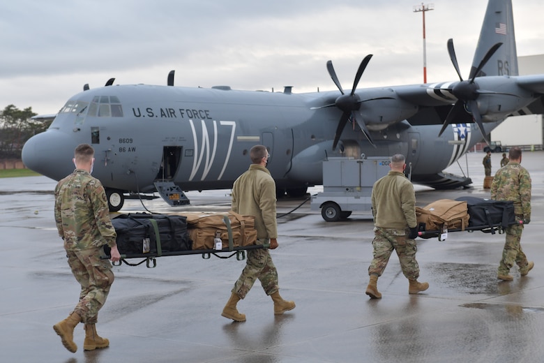 Airmen carrying supplies on stretchers toward a plane.
