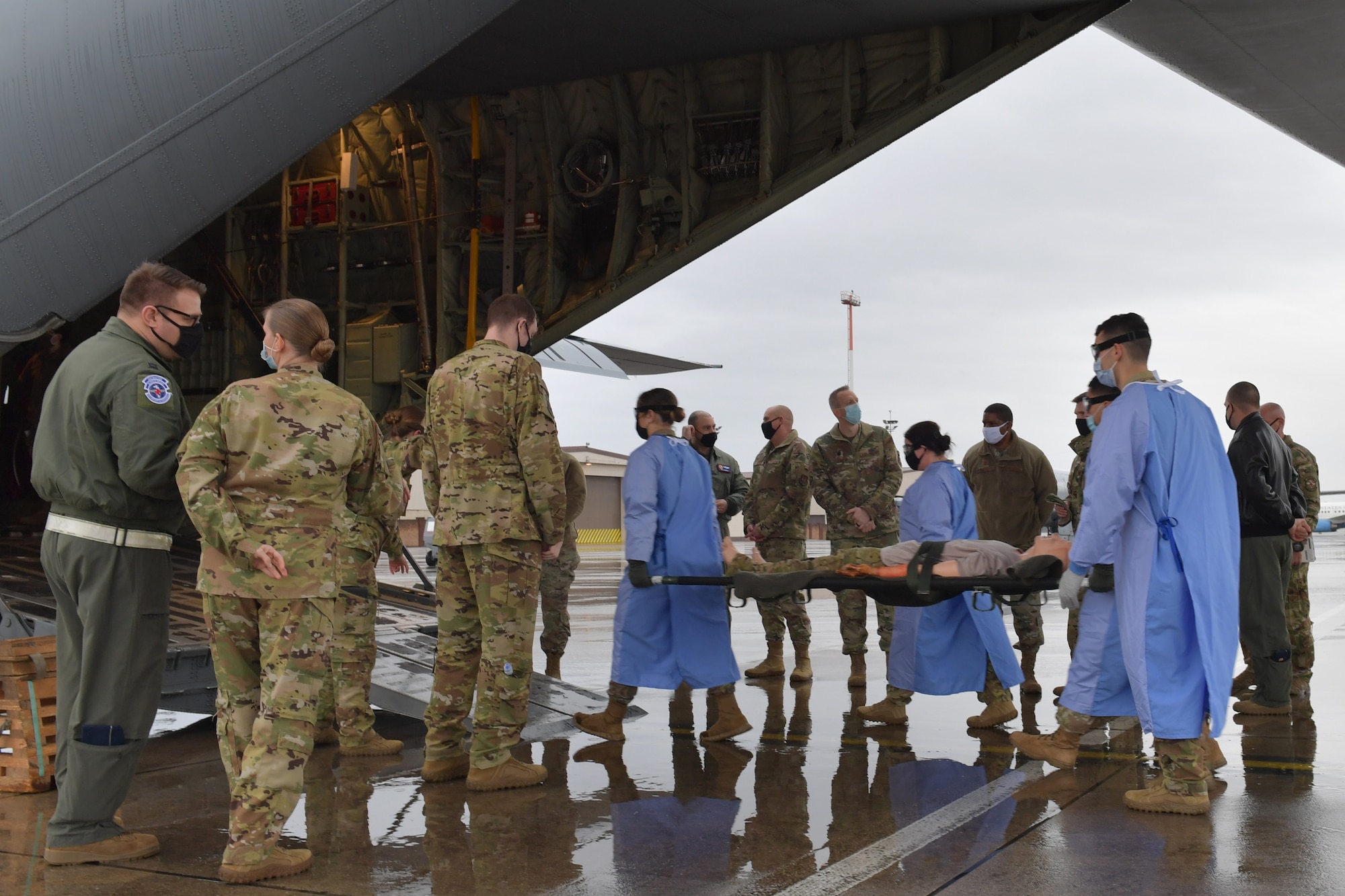 Airmen walking a mannequin on a stretcher onto a plane.