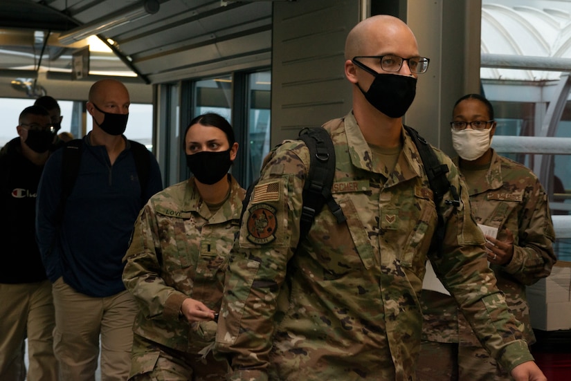 Masked passengers exit a terminal.