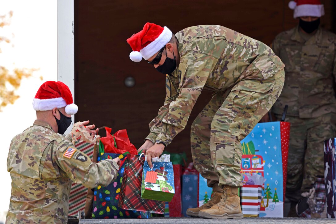 A soldier hands gift bags to another soldier.