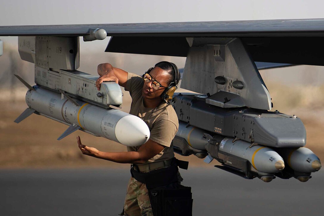 An airman inspects a munition on an aircraft.