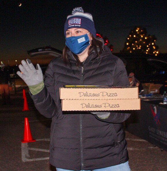 Katie Barley, United Service Organizations operations supervisor, waves at cars during the USO’s No Dough Dinner Drive Thru at Schriever Air Force Base, Colorado, Dec. 16, 2020. The event provided dinner to more than 100 families who drove to the base’s event center to collect their meal. (U.S. Space Force photo by Marcus Hill)