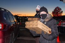 United Service Organizations volunteers Mary and Dennis Sparrow view the line of vehicles as they prepare to hand out pizzas Dec. 16, 2020, at Schriever Air Force Base, Colorado. Families also got beverages DVDs and calendars from the event. (U.S. Space Force photo by Marcus Hill)