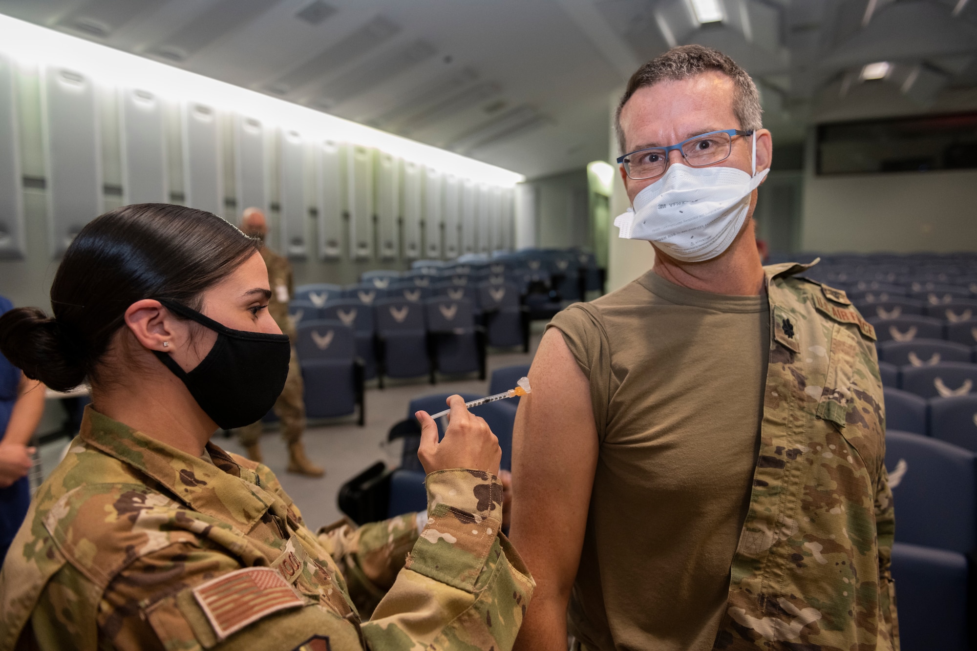 U.S. Air Force Tech. Sgt. Yadira Wood, 60th Aeromedical Evacuation Squadron aerospace medical technician, administers the COVID-19 vaccine to Lt. Col. Joseph Sky, 60th Surgical Squadron chief of medical staff, Dec. 22, 2020, at Travis Air Force Base, California. Sky was the first person to receive the vaccine at Travis AFB. Sky will join several Airmen from the 60th Medical Group on a deployment to Southern California to assist with pandemic relief efforts. David Grant U.S. Air Force Medical Center is the largest Air Force medical facility and provides care to more than 276,000 Department of Defense and Veteran Affairs eligible beneficiaries. Essential medical personnel from the 60th Medical Group were the first to receive the vaccine at Travis AFB. (U.S. Air Force photo by Senior Airman Cameron Otte)