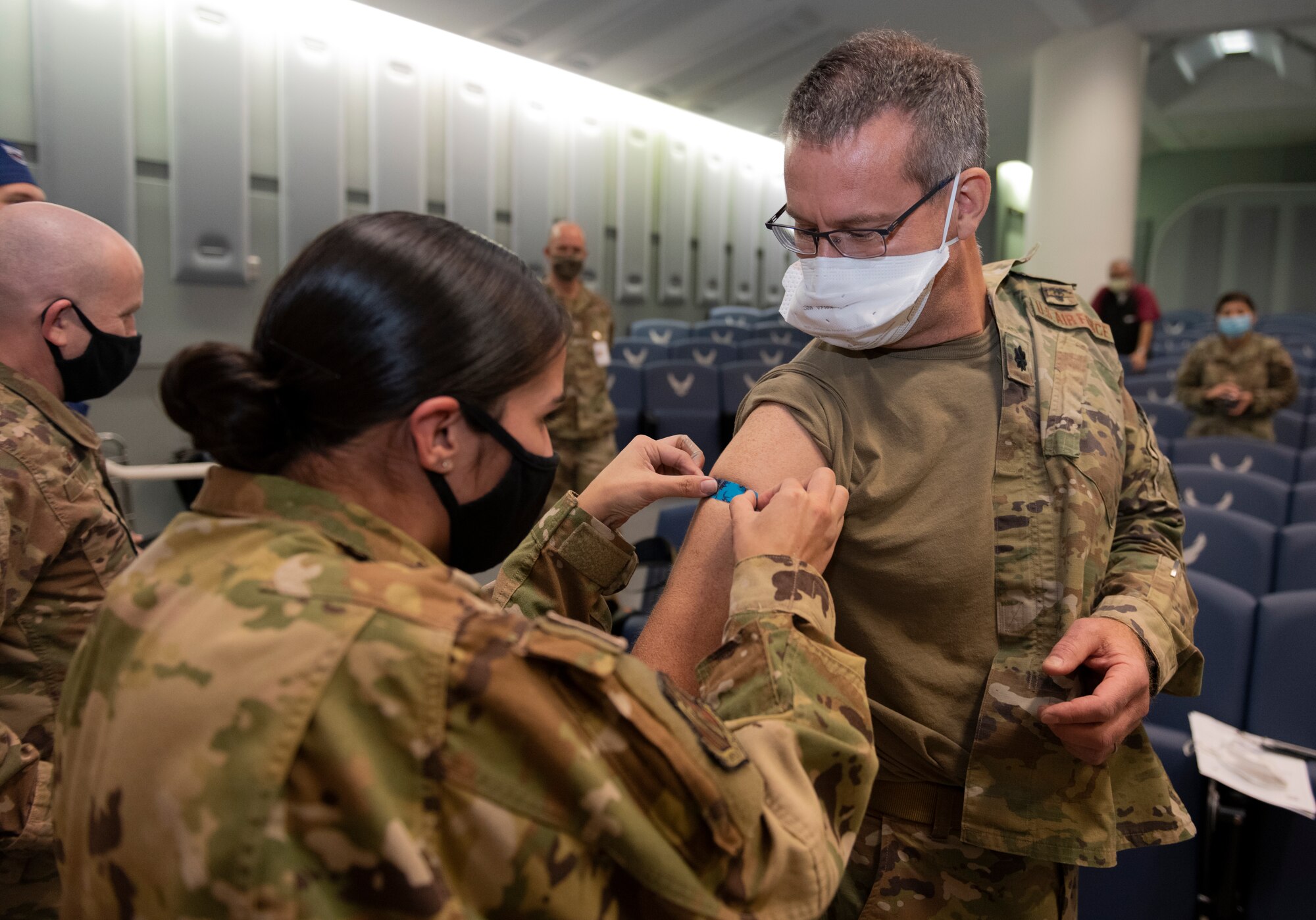 U.S. Air Force Tech. Sgt. Yadira Wood, 60th Aeromedical Evacuation Squadron aerospace medical technician, places a band aid on the right arm of Lt. Col. Joseph Sky, 60th Surgical Squadron chief of medical staff, after administering the COVID-19 vaccine to Sky Dec. 22, 2020, at Travis Air Force Base, California. David Grant U.S. Air Force Medical Center is the largest Air Force medical facility and provides care to more than 276,000 Department of Defense and Veteran Affairs eligible beneficiaries. Essential medical personnel from the 60th Medical Group were the first to receive the vaccine at Travis AFB. (U.S. Air Force photo by Senior Airman Cameron Otte)