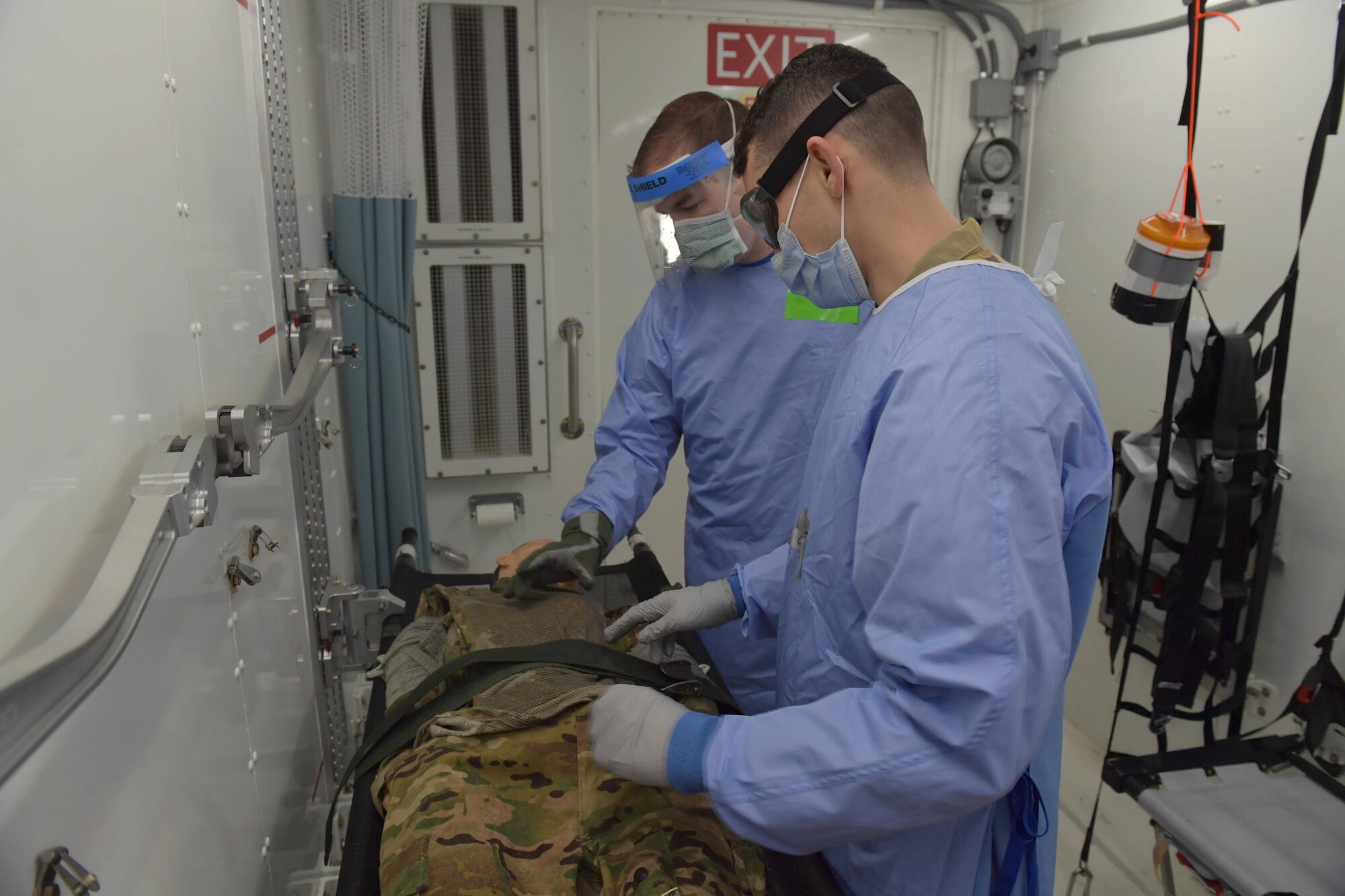 Two Airmen standing next to a mannequin on a gurney.