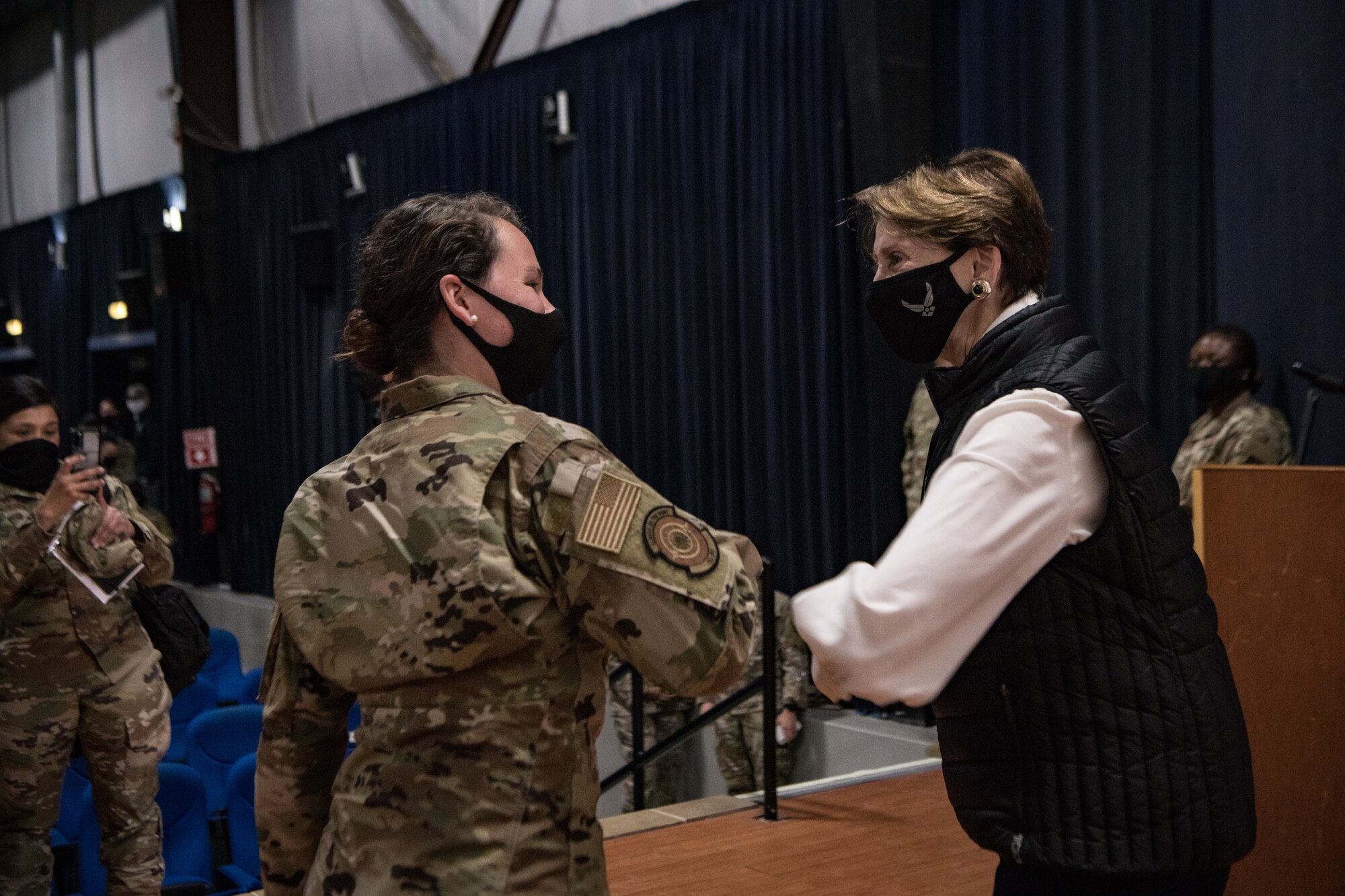 Secretary of the Air Force Barbara Barrett elbow bumps an Airman on the stage