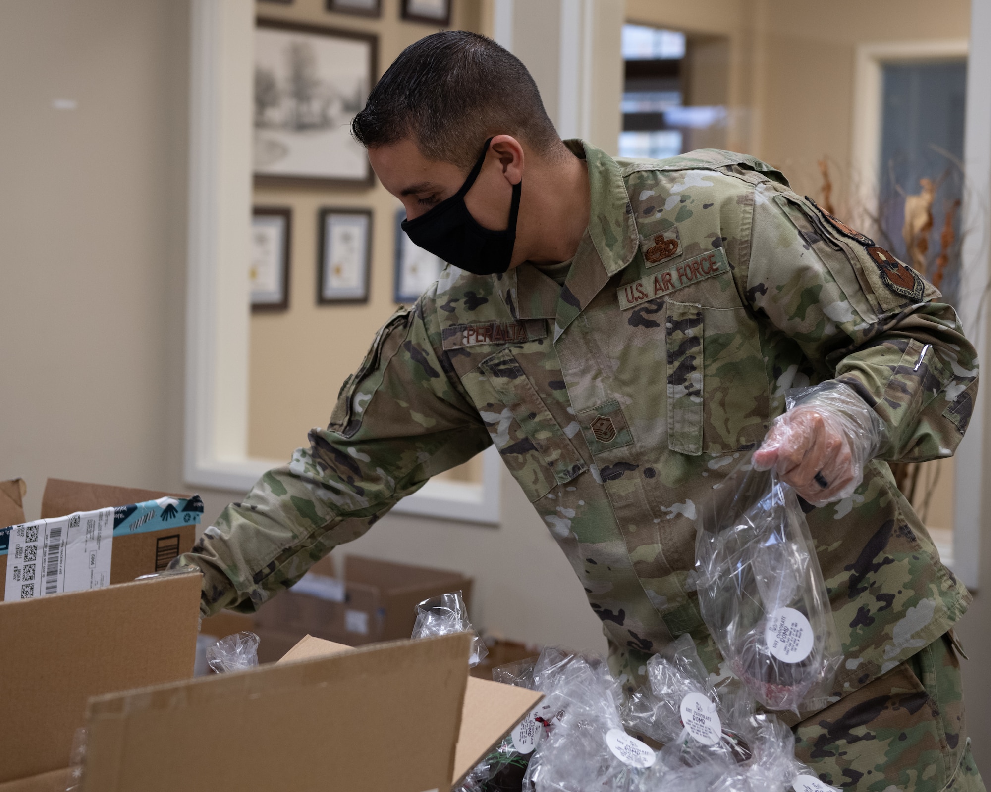 Master Sgt. Roberto Peralta, Jeanne M. Holm Center for Officer Accessions and Citizen Development first sergeant places baked goods into bags for Airmen Dec. 16, 2020, at the Hunt Housing Offices on Maxwell Air Force Base, Alabama. Volunteers repackaged donated cookies and other baked goods while wearing masks and gloves to reduce the risk of COVID-19 transmission.