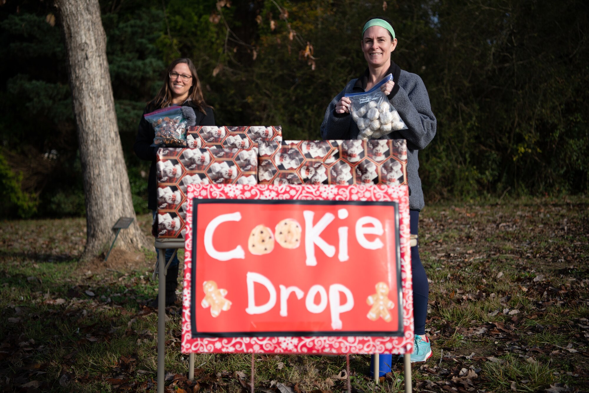 Kristen Morgan and Stephanie Turner, volunteers for the Maxwell-Gunter Holiday Cookie Drive, pose for a photo by the drive-thru cookie drop-off by Montgomery Elementary/Middle School Dec. 16, 2020, on Maxwell Air Force Base, Alabama. Volunteers wore masks and set up their cookie drop-off table outside to mitigate the risks of COVID-19 transmission and ensure the cookie drive could take place safely amid the pandemic.