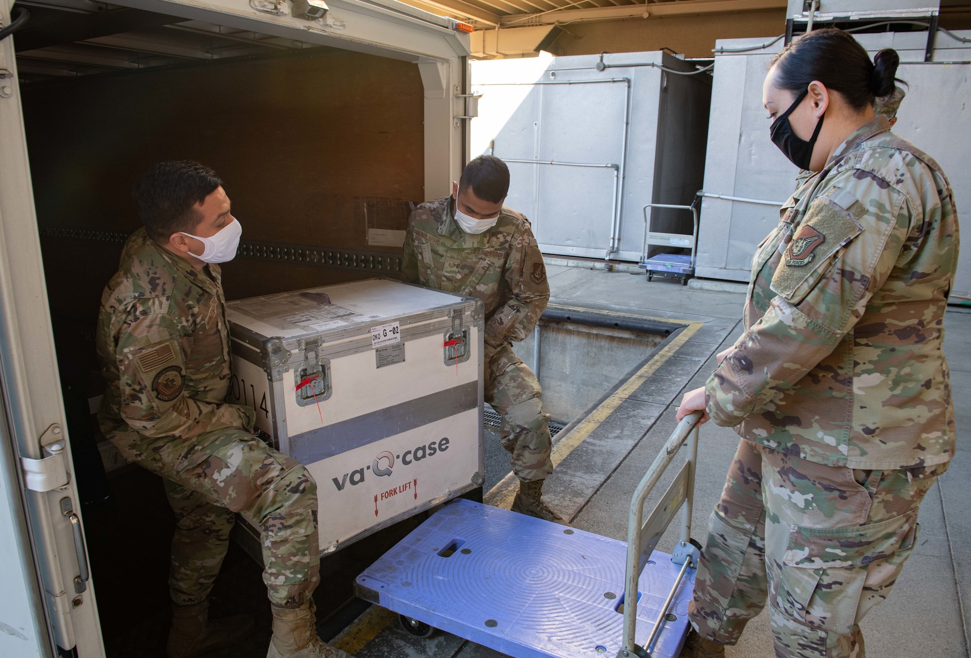 Members of the 374th Medical Group load the first shipment of Moderna COVID-19 vaccines onto a cart at Yokota Air Base