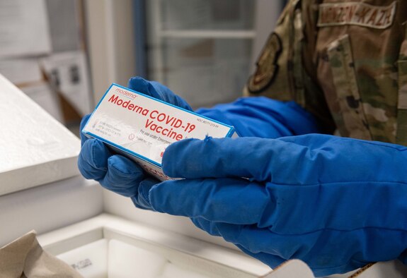 Staff Sgt. Daniel Monzon-Kazhe, 374th Medical Group non-commissioned officer in charge of contingency material, holds a box of Moderna COVID-19 vaccines