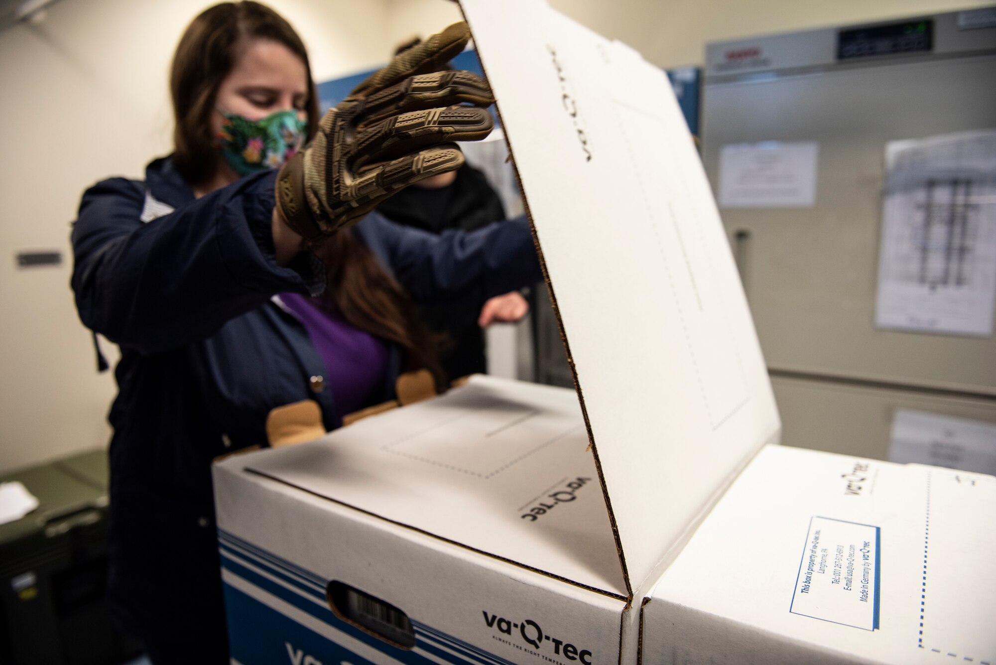 U.S. Air Force Staff Sgt. Anna Murray, 48th Medical Group immunizations technician, opens the first box of COVID-19 vaccinations delivered to Royal Air Force Lakenheath, England, Dec. 27, 2020. Initial quantities of the vaccine are limited and will be distributed on a rolling delivery basis as more vaccines become available. (U.S. Air Force photo by Airman 1st Class Jessi Monte)