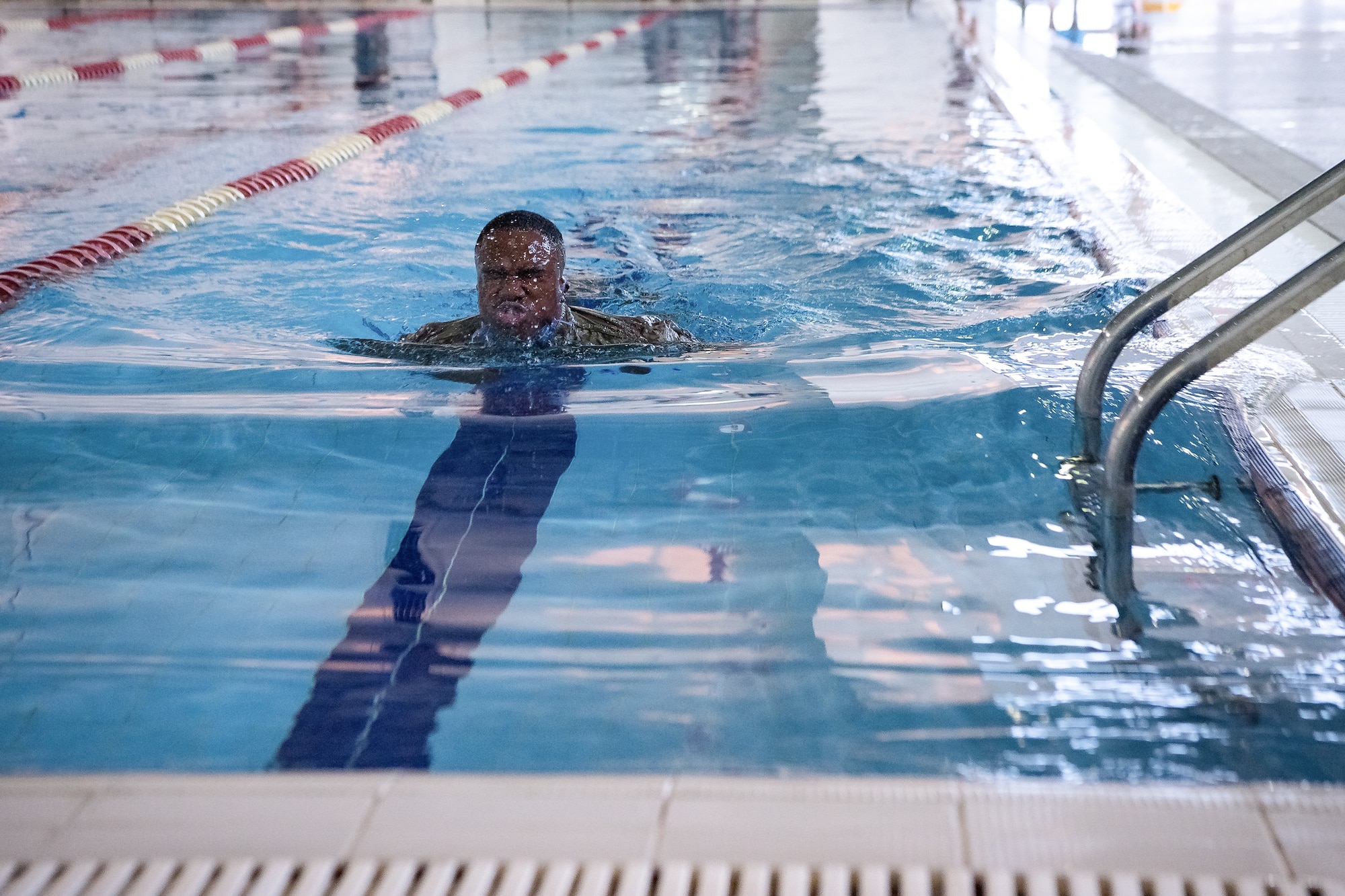 a man swims wearing a military uniform
