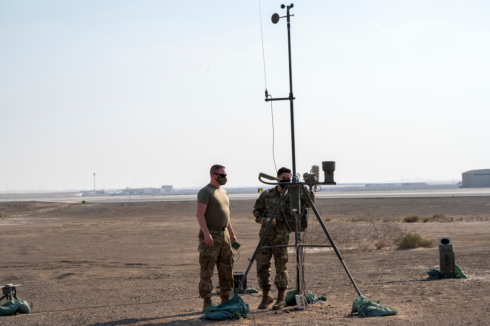 U.S. Air Force Master Sgt. Adam Garrison (left), 380th Expeditionary Operations Support Squadron (EOSS) weather flight chief, and U.S. Air Force Senior Airman Ricardo Solis-Arroyo (right), 380th EOSS weather forecaster, install a newer Tactical Meteorological Observing System (TMOS) at Al Dhafra Air Base, United Arab Emirates, Dec. 23, 2020.