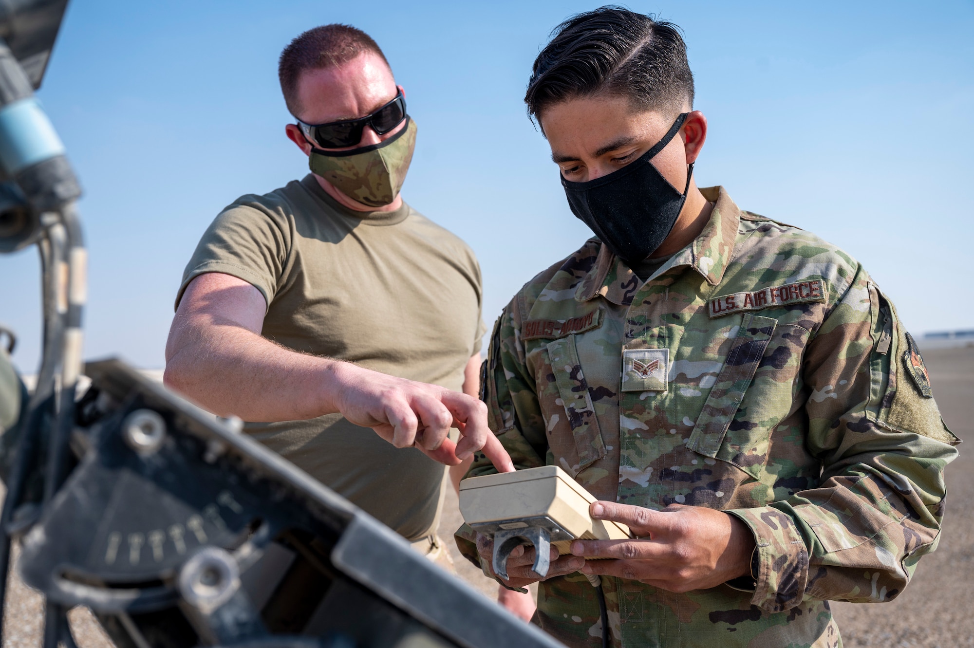 U.S. Air Force Master Sgt. Adam Garrison (left), 380th Expeditionary Operations Support Squadron (EOSS) weather flight chief, shows U.S. Air Force Senior Airman Ricardo Solis-Arroyo (right), 380th EOSS weather forecaster, how to control a Tactical Meteorological Observing System (TMOS) remote during an installation of a newer TMOS at Al Dhafra Air Base, United Arab Emirates, Dec. 23, 2020.