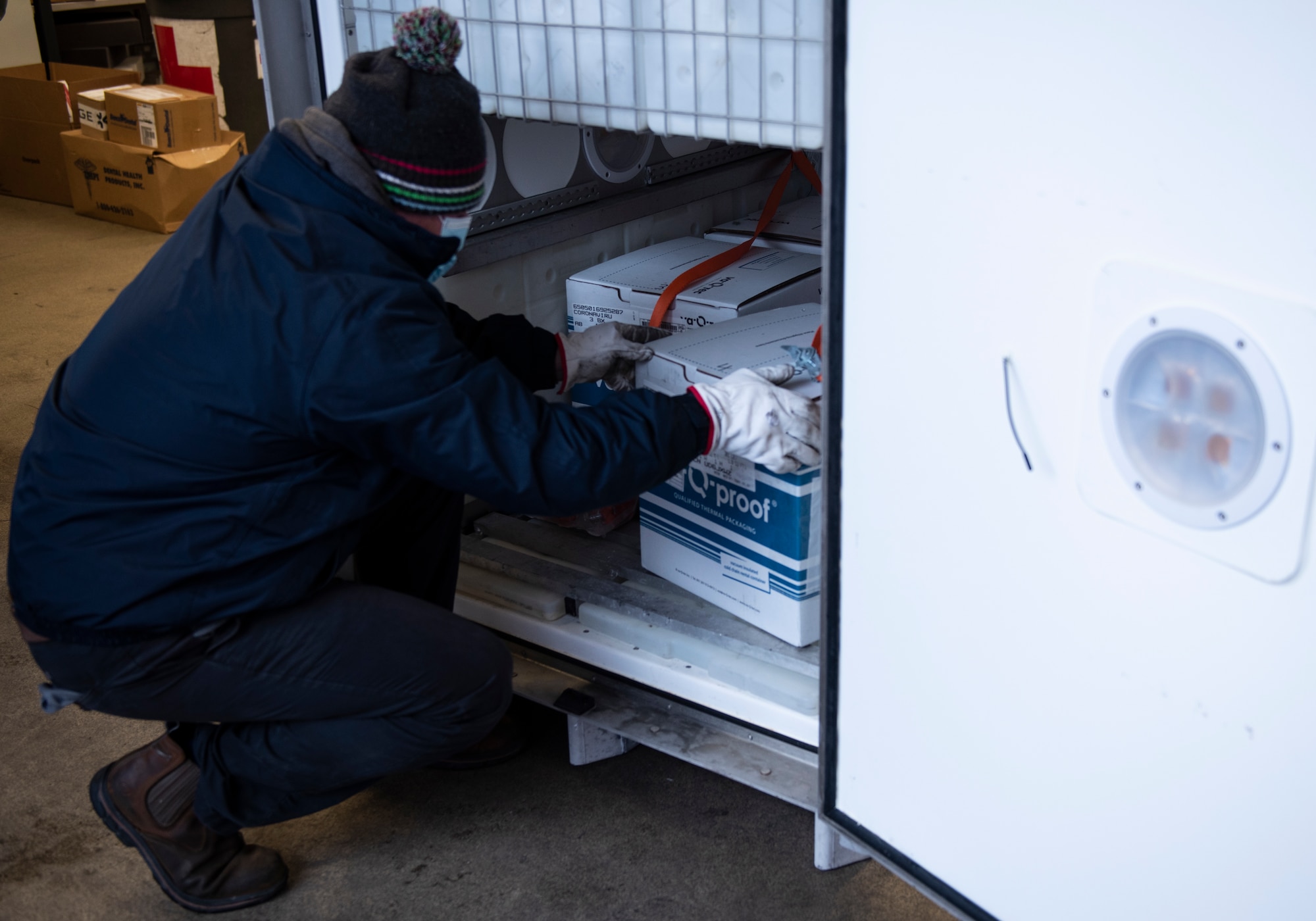 Delivery personnel removes boxes of COVID-19 vaccinations from a temperature-controlled vessel at Royal Air Force Lakenheath, England, Dec. 27, 2020. The United States Government has purchased the vaccines and is making them available to the Department of Defense for distribution and administration to DoD personnel. (U.S. Air Force photo by Airman 1st Class Jessi Monte)