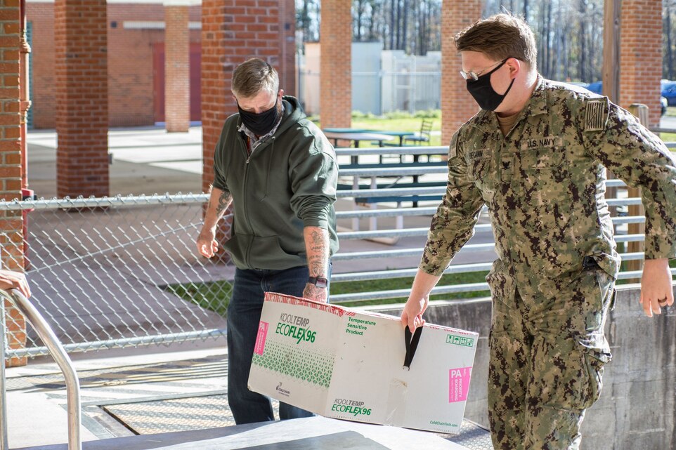 Personnel with Naval Health Clinic Cherry Point (NHCCP), North Carolina, carry in the first shipment of the Moderna COVID-19 Vaccine at Marine Corps Air Station Cherry Point, North Carolina, on Dec. 22, 2020.