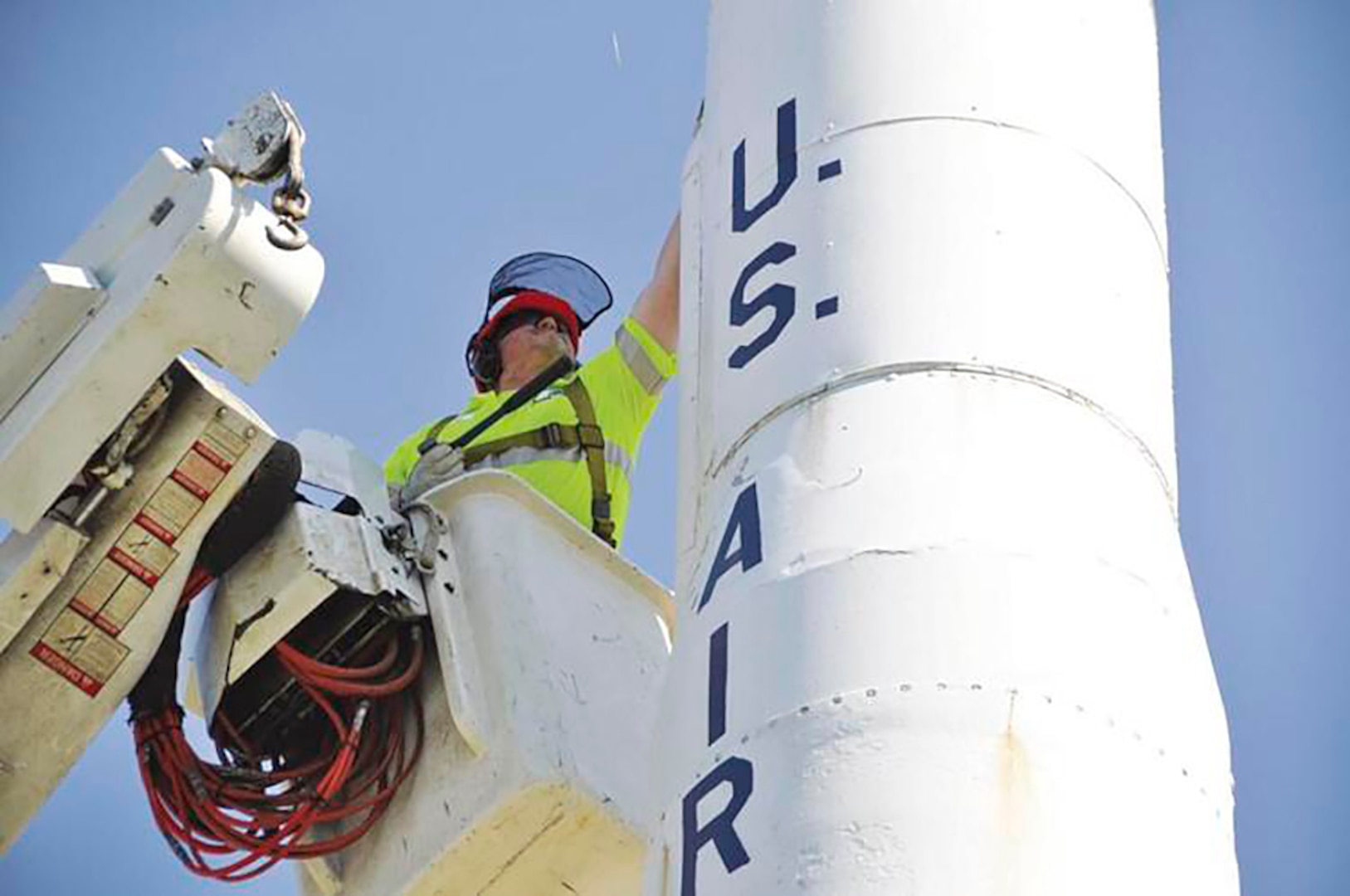 A man in a bucket pole examines an old missile.