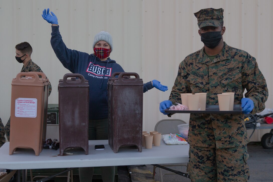 Marines and civilian volunteers from 1st Maintenance Battalion provide hot chocolate to families during the battalion’s Winter Wonderland.