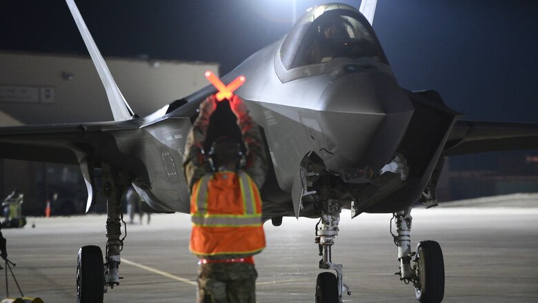 An Air Force maintainer stops an F-35A Lightning II on a flight line.