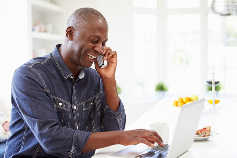 man using laptop and cell phone at home