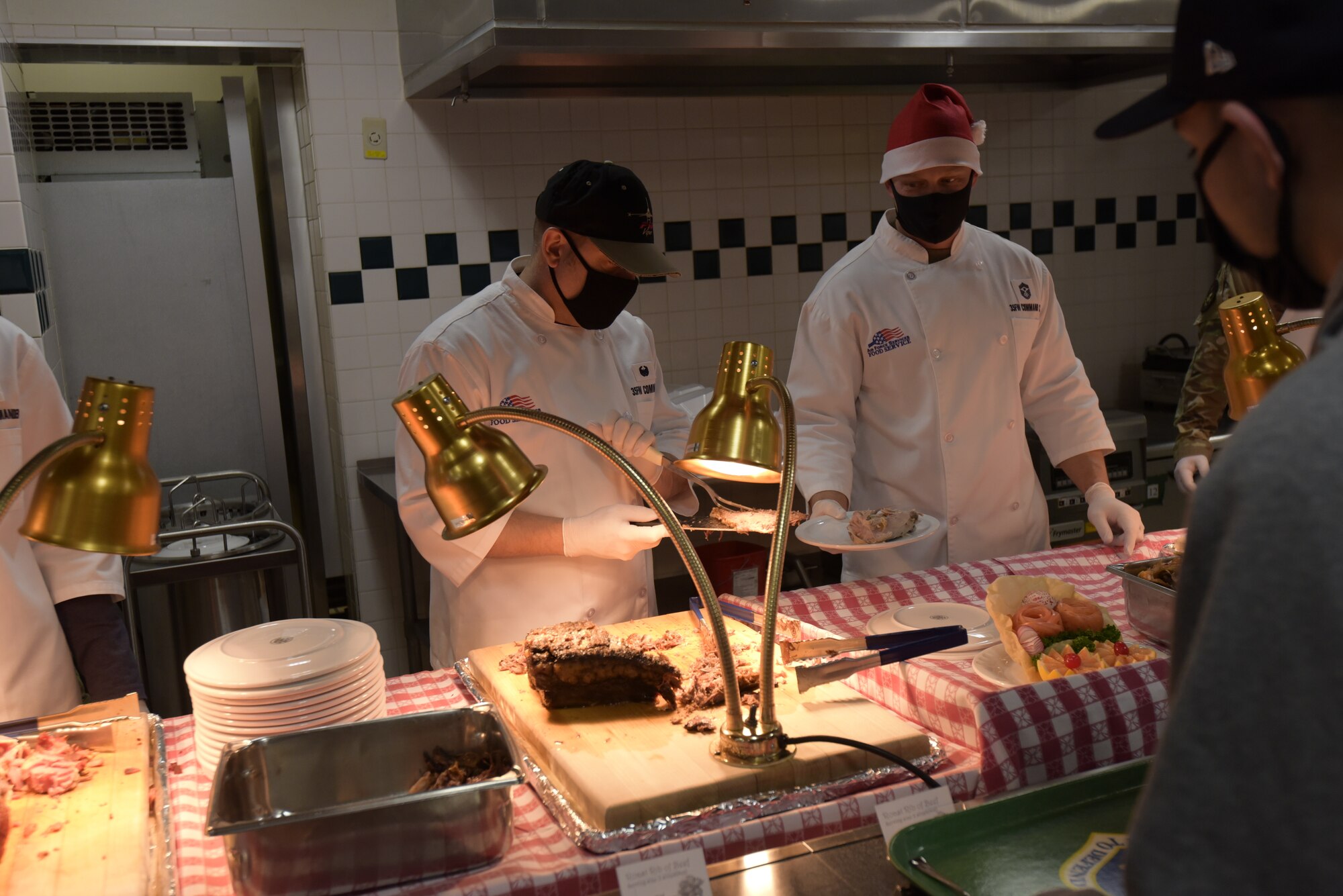 U.S. Air Force Chief Master Sergeant Joey R. Meininger, 35th Fighter Wing command chief, right, passes a plate to Col. Jesse J. Friedel, 35th FW commander, as they serve an Airman for a special holiday meal at the 35th Force Support Squadron Grissom Dining Facility, Misawa Air Base, Japan, Dec. 25, 2020. The holiday meal is a special meal prepared by the 35th Force Support Squadron and served by senior leaders each year. (U.S. Air Force photo by Airman 1st Class Joao Marcus Costa)