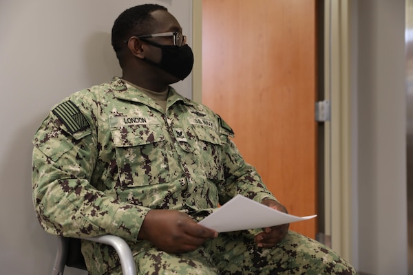 Navy Petty Officer 2nd Class John London sits outside a waiting room before receiving one the first COVID-19 vaccines at Brian D. Allgood Army Community Hospital.