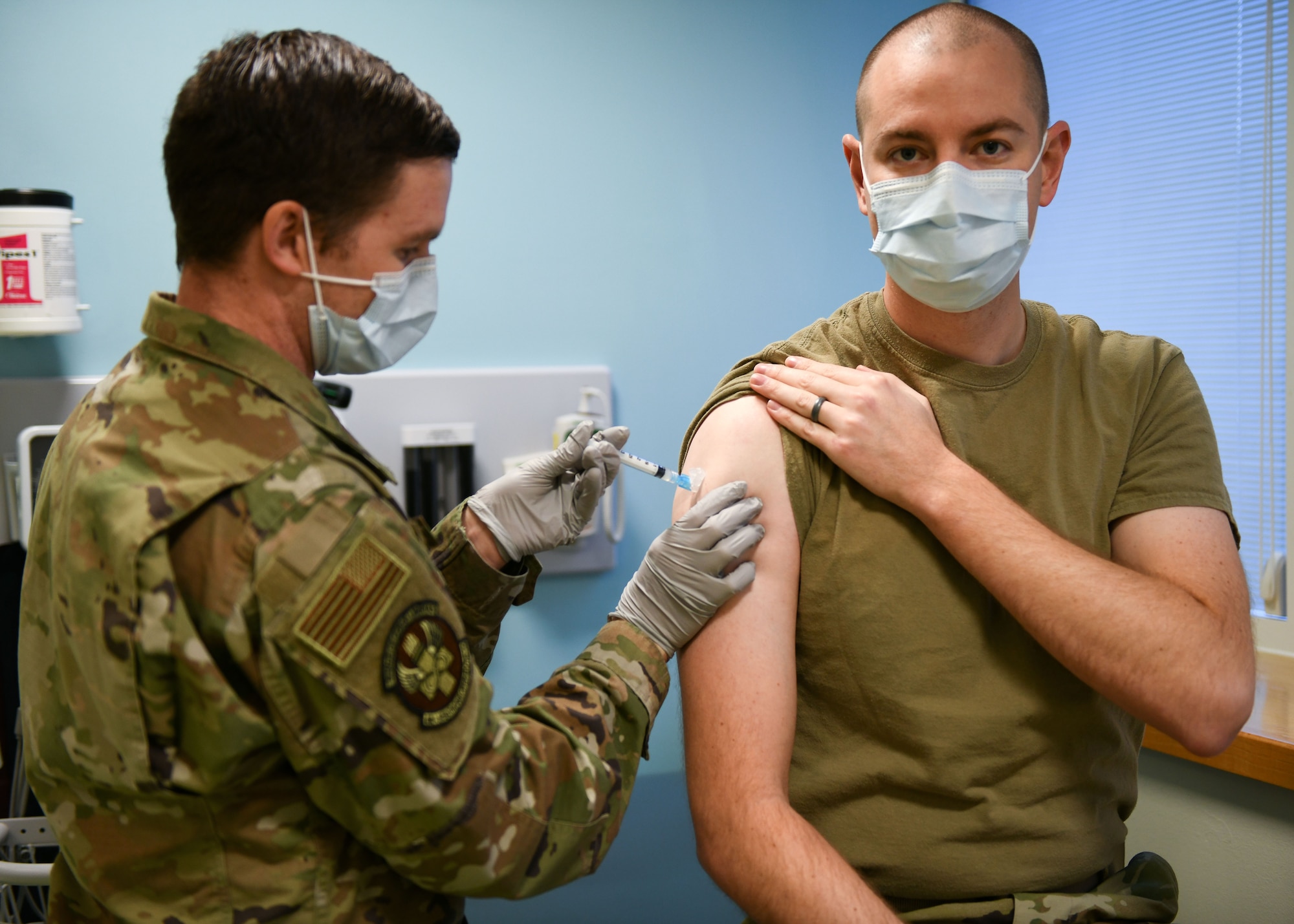 Technical Sgt. Justin Pribble, 48th Medical Group pediatrics/immunology flight chief, administers the first COVID-19 vaccine to Capt. Branden Hunsaker, 48th Medical Group emergency physician, at Royal Air Force Lakenheath, England, Dec. 29, 2020. The initial shipment of vaccines will be limited to healthcare workers and first responders. As the distribution is carried out, information on subsequent phases will be provided through command channels and installation web and social media channels. (U.S. Air Force photo by Senior Airman Madeline Herzog)