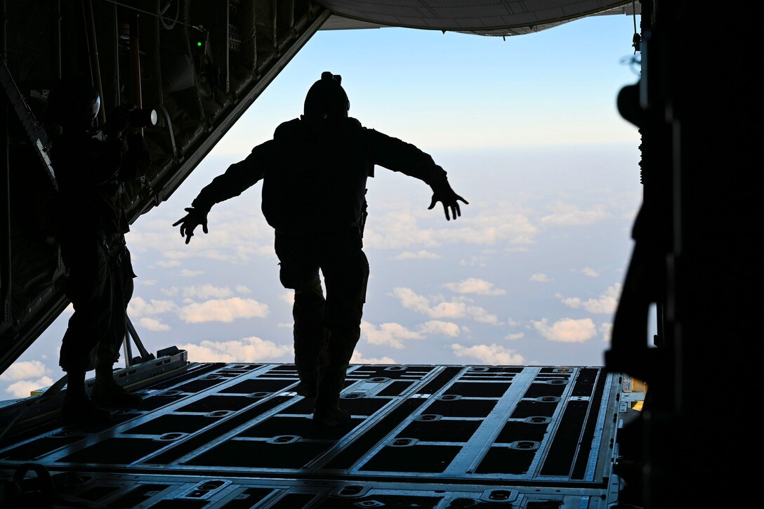 An airman shown in silhouette stands at the back of an aircraft.