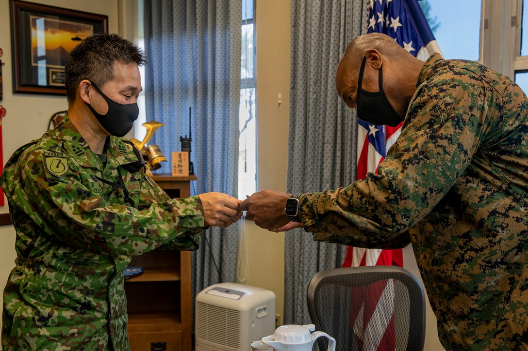 U.S. Marine Corps Col. Henry Dolberry Jr., Marine Corps Air Station (MCAS) Futenma commanding officer, and Japan Ground Self Defense Force (JGSDF) Col. Nobuyuki Ishii, 22nd Rapid Deployment Regiment commander, exchange business cards during a tour at Marine Corps Air Station Futenma, Okinawa, Japan, Nov. 4, 2020. The tour was an opportunity for the JGSDF to conduct a site survey to familiarize themselves with MCAS Futenma’s capabilities. (U.S. Marine Corps photo by Lance Cpl. Zachary Larsen)