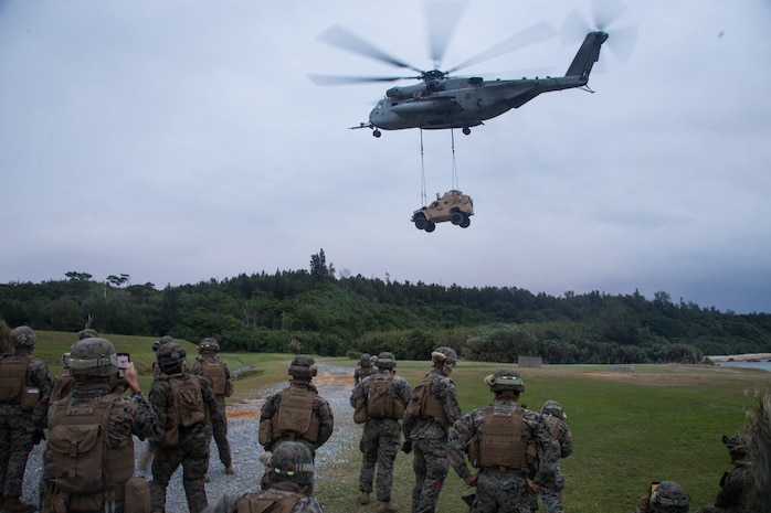 U.S. Marines with Combat Logistics Battalion 31, 31st Marine Expeditionary Unit (MEU) observe a Marine CH-53E Super Stallion aircraft assigned to Marine Medium Tiltrotor Squadron 262 (Reinforced), 31st MEU, carrying a Joint Light Tactical Vehicle Heavy Guns Carrier during a Helicopter Support Team (HST) training exercise as part of MEU Exercise at Kin Blue, Okinawa, Japan on Dec. 17, 2020. HST training is conducted to increase proficiency in logistics tasks and enhance the ability to execute potential contingency missions carried out by the 31st MEU. The 31st MEU, the Marine Corps only continuously forward-deployed MEU, provides a flexible and lethal force ready to perform a wide range of military operations as the premiere crisis response force in the Indo-Pacific region. (U.S. Marine Corps photo by Lance Cpl. Colton Nicks)