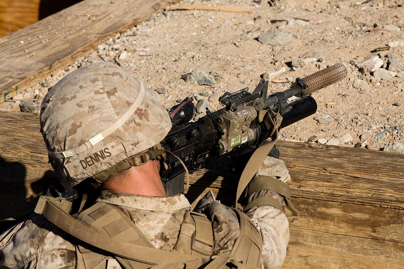 A Marine uses a suppressor while shooting a gun.