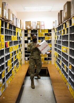 Postal clerk carries a package.