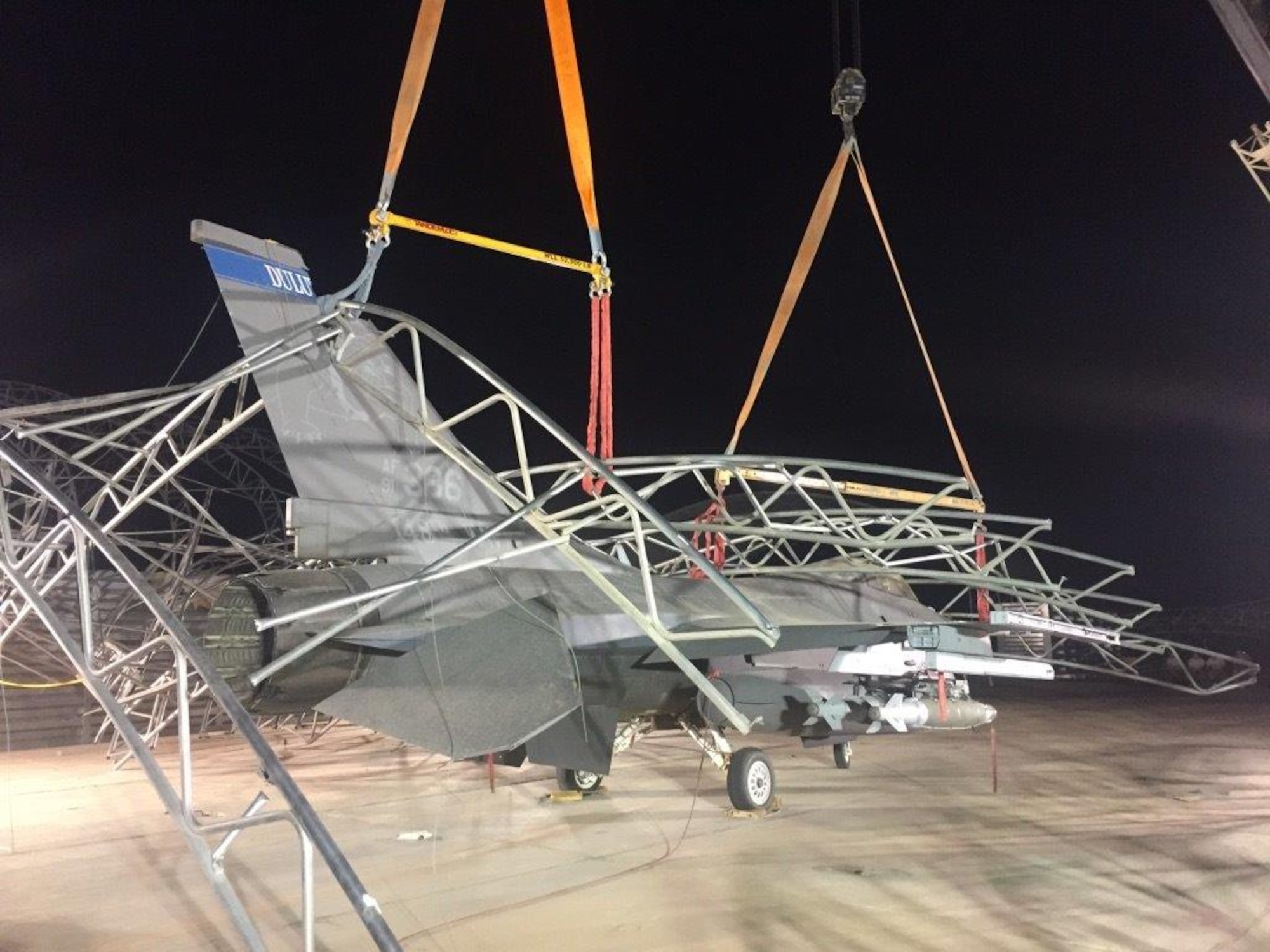 Civil Engineers and aircraft maintenance personnel untangle and remove sunshades after they collapsed on F-16 Fighting Falcons during a storm that caused 91-mile per hour winds at the 407th Air Expeditionary Group in 2018.