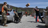 Vermont National Guard Soldiers and state partners hustle to load meals into vehicles in Peru, Vermont, May 19, 2020. The Vermont National Guard assists the Vermont Food Bank "Farmers to Families" program and Vermont Emergency Management provide fresh produce, dairy and prepared meals.