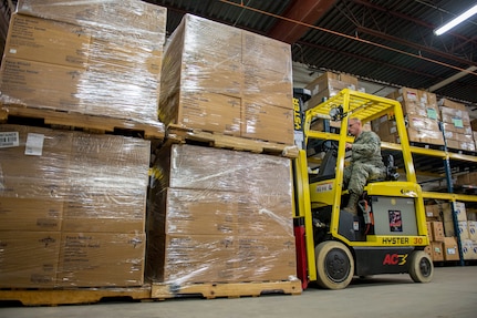 Air Force Staff Sgt. Keith Gomo helps the Vermont Department of Health unload pallets of medical supplies at a distribution center in Vermont March 31, 2020. The Vermont National Guard is working with the state of Vermont and emergency response partners in a whole-of-government effort to flatten the curve of the COVID-19 pandemic. Gomo is assigned to the 158th Logistics Readiness Squadron.