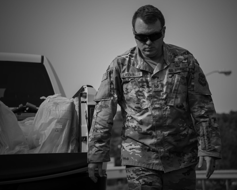 An airman in sunglasses walks away from a pickup truck loaded with supplies.