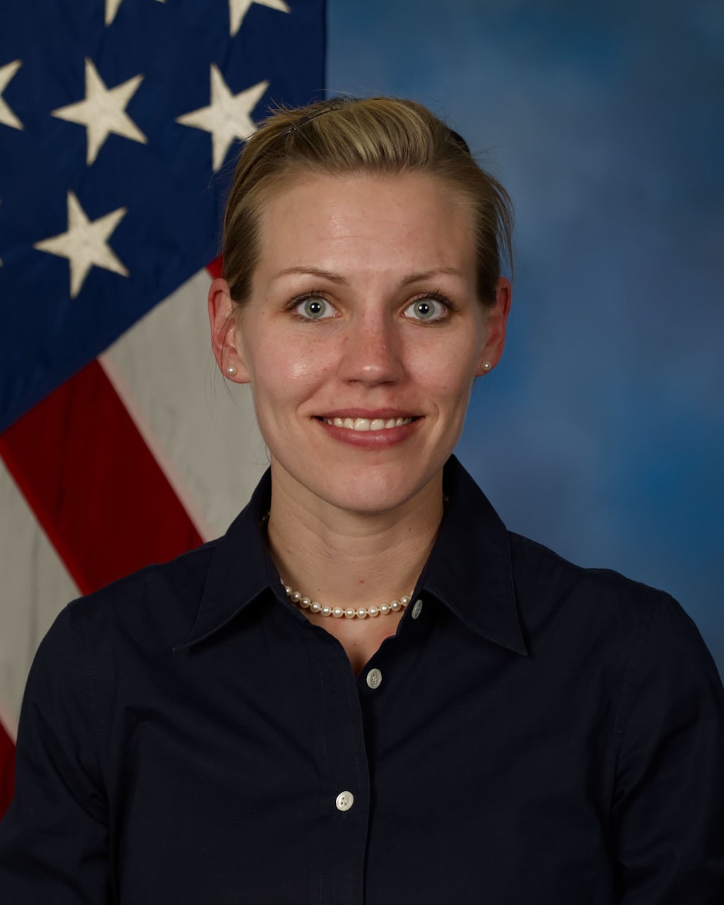 A woman poses for a professional portrait in front of a U.S. flag.