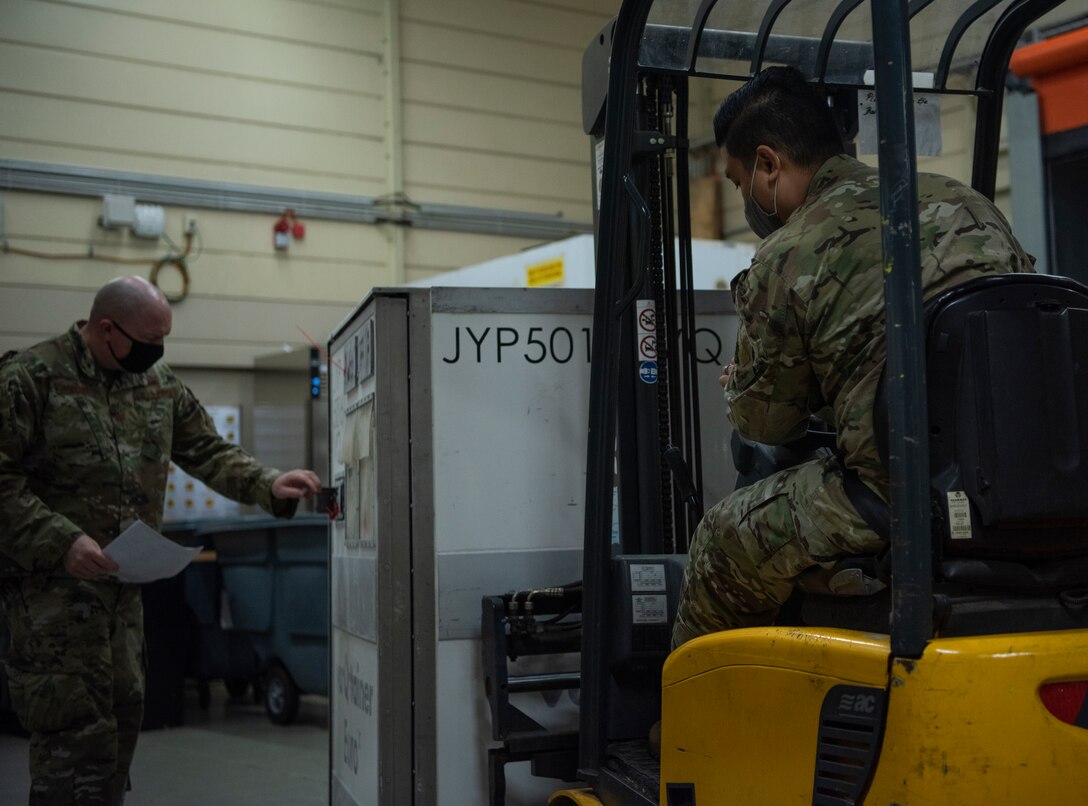 Airmen offload an initial shipment of COVID-19 vaccines at Ramstein Air Base, Germany, Dec. 30, 2020.