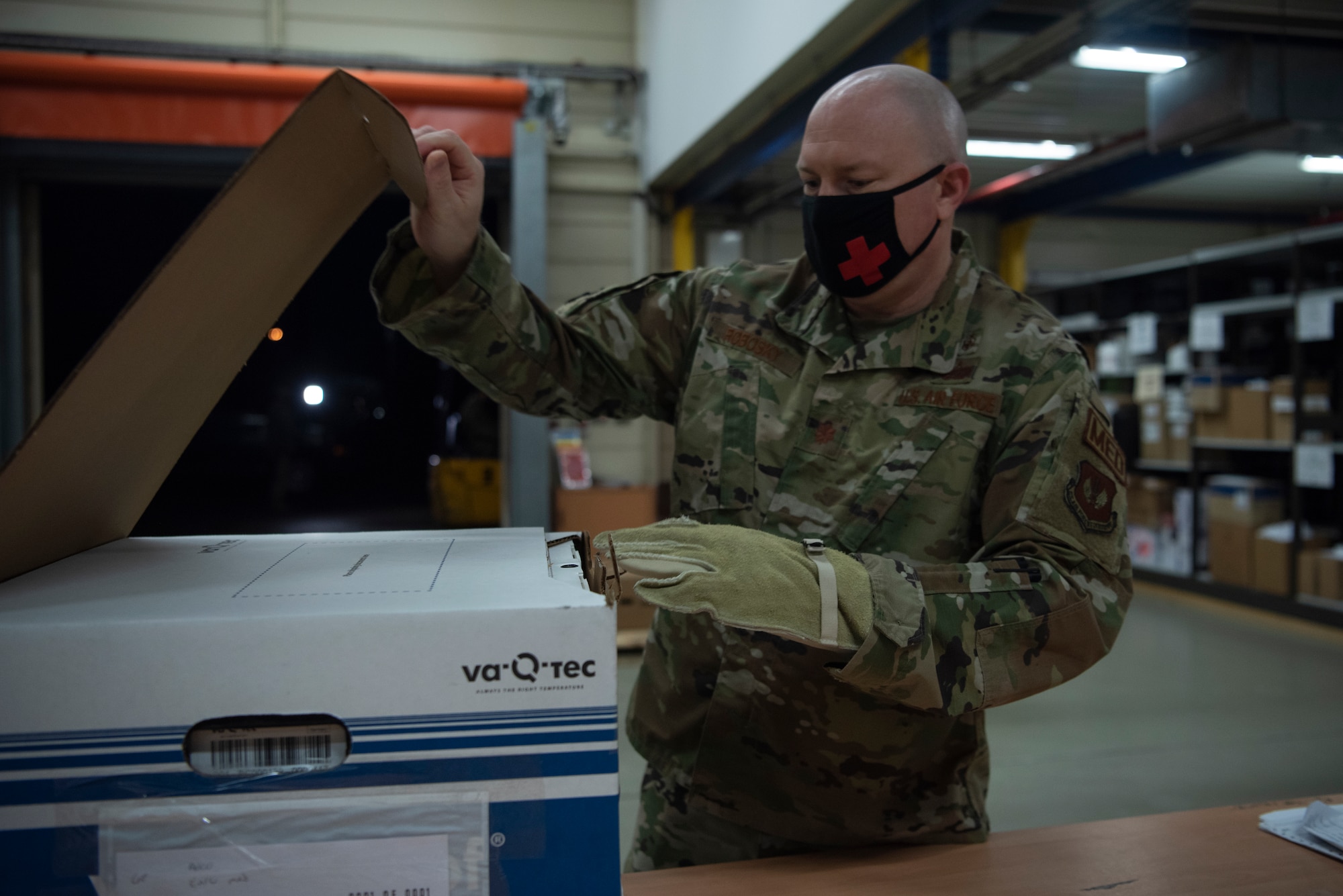U.S. Air Force Maj. Christopher Robosky, 86th Medical Group medical logistics flight commander, opens a box containing COVID-19 vaccinations at Ramstein Air Base, Germany, Dec. 30, 2020.