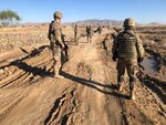 Sgt. Douglas King, of the Wisconsin Army National Guard's 829th Engineer Company assesses a road repair project in Afghanistan with a Romanian soldier in April 2020.