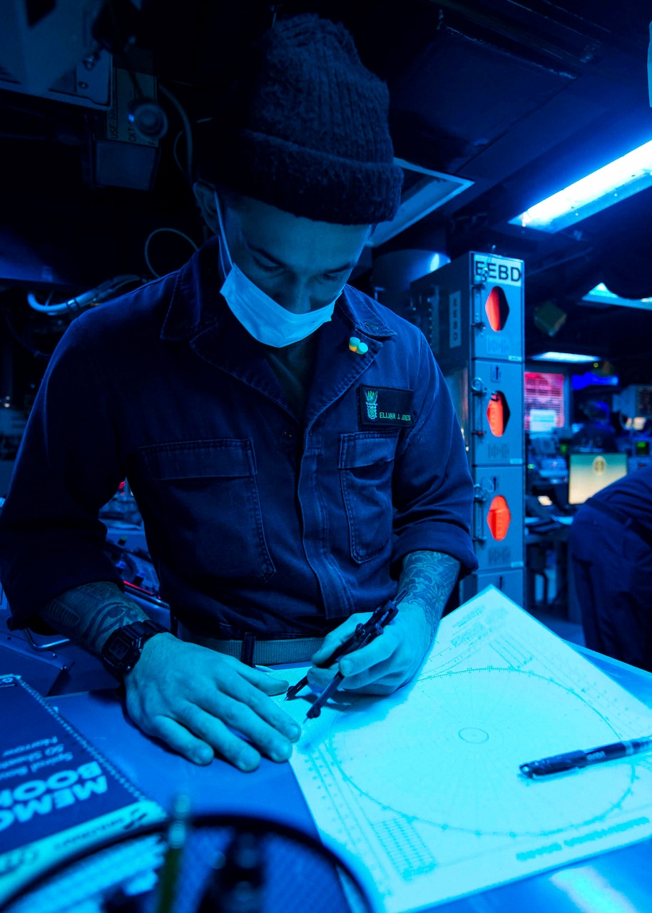 TAIWAN STRAIT (Dec. 30, 2020) Ensign Elijah Jones, from San Bernardino, California, plots on a maneuvering board in the combat information center as the guided-missile destroyer USS Curtis Wilbur (DDG 54) conducts routine operations. Curtis Wilbur is forward-deployed to the U.S. 7th Fleet area of operations in support of a free and open Indo-Pacific.