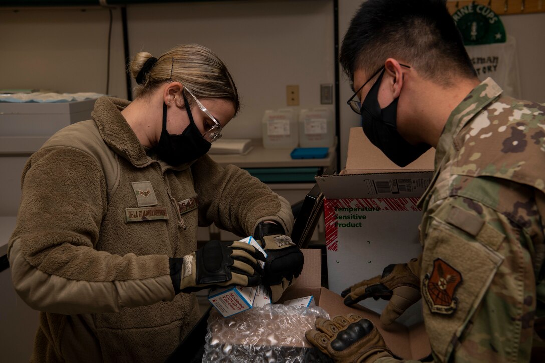 U.S. Air Force Airman 1st Class Jennifer De La Guardia Rodriguez, 509th Healthcare Operations Squadron medical logistics technician, left, and Staff Sgt. Allen Magbutay, 509th HCOS NCO in charge of medical materiel, examine the first shipment of the COVID-19 vaccine at Whiteman Air Force Base, Missouri, Dec. 30, 2020. The Whiteman AFB COVID-19 vaccine distribution and administration plan will implement a phased, standardized and coordinated strategy for prioritizing, distributing, and administering COVID-19 vaccines to installation personnel. (U.S. Air Force photo by Staff Sgt. Dylan Nuckolls)