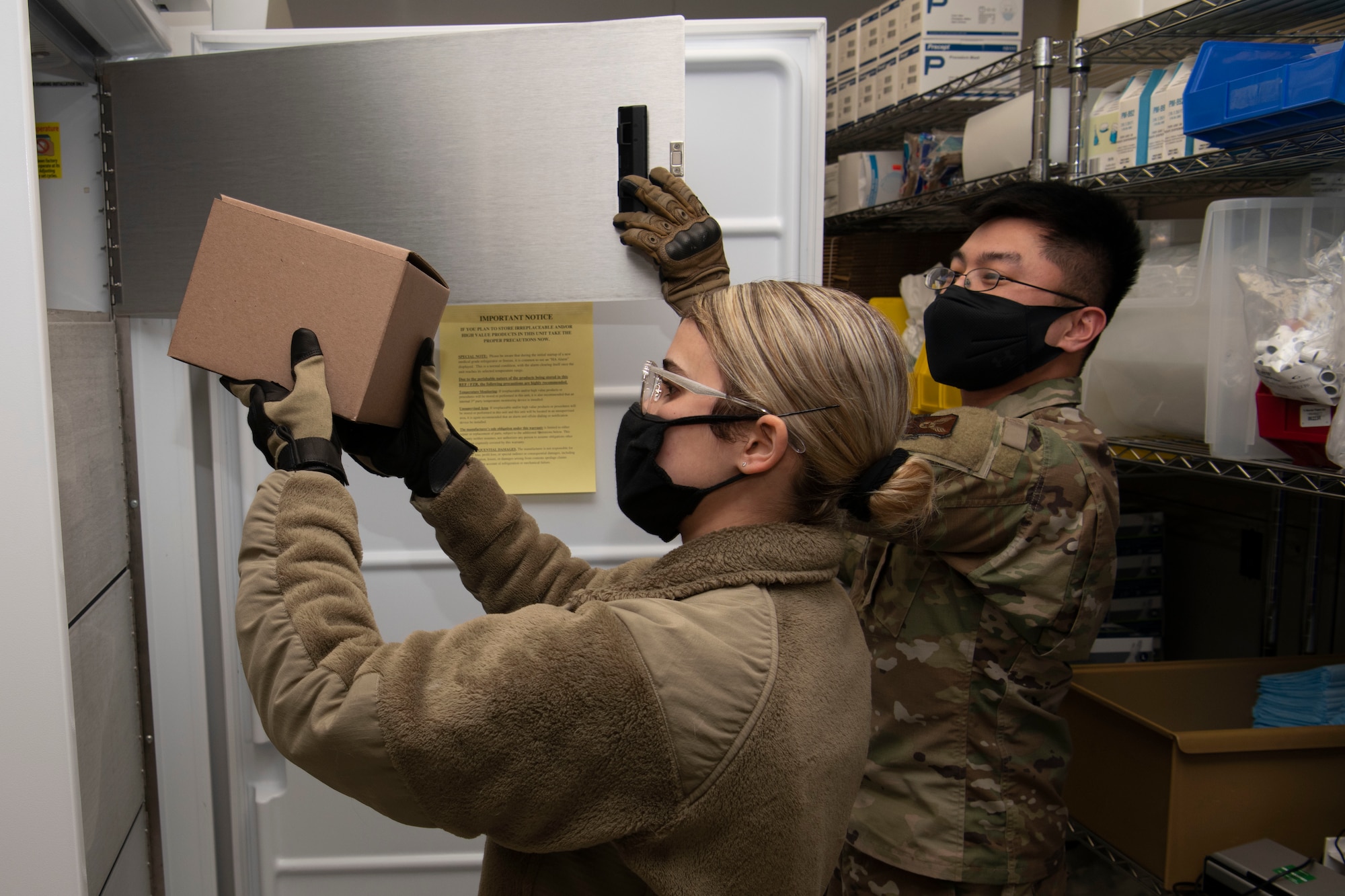 U.S. Air Force Airman 1st Class Jennifer De La Guardia Rodriguez, 509th Healthcare Operations Squadron medical logistics technician, left, and Staff Sgt. Allen Magbutay, 509th HCOS NCO in charge of medical materiel, place the first shipment of the COVID-19 vaccine in the freezer at Whiteman Air Force Base, Missouri, Dec. 30, 2020. The Whiteman AFB COVID-19 vaccine distribution and administration plan will implement a phased, standardized and coordinated strategy for prioritizing, distributing, and administering COVID-19 vaccines to installation personnel. (U.S. Air Force photo by Staff Sgt. Dylan Nuckolls)