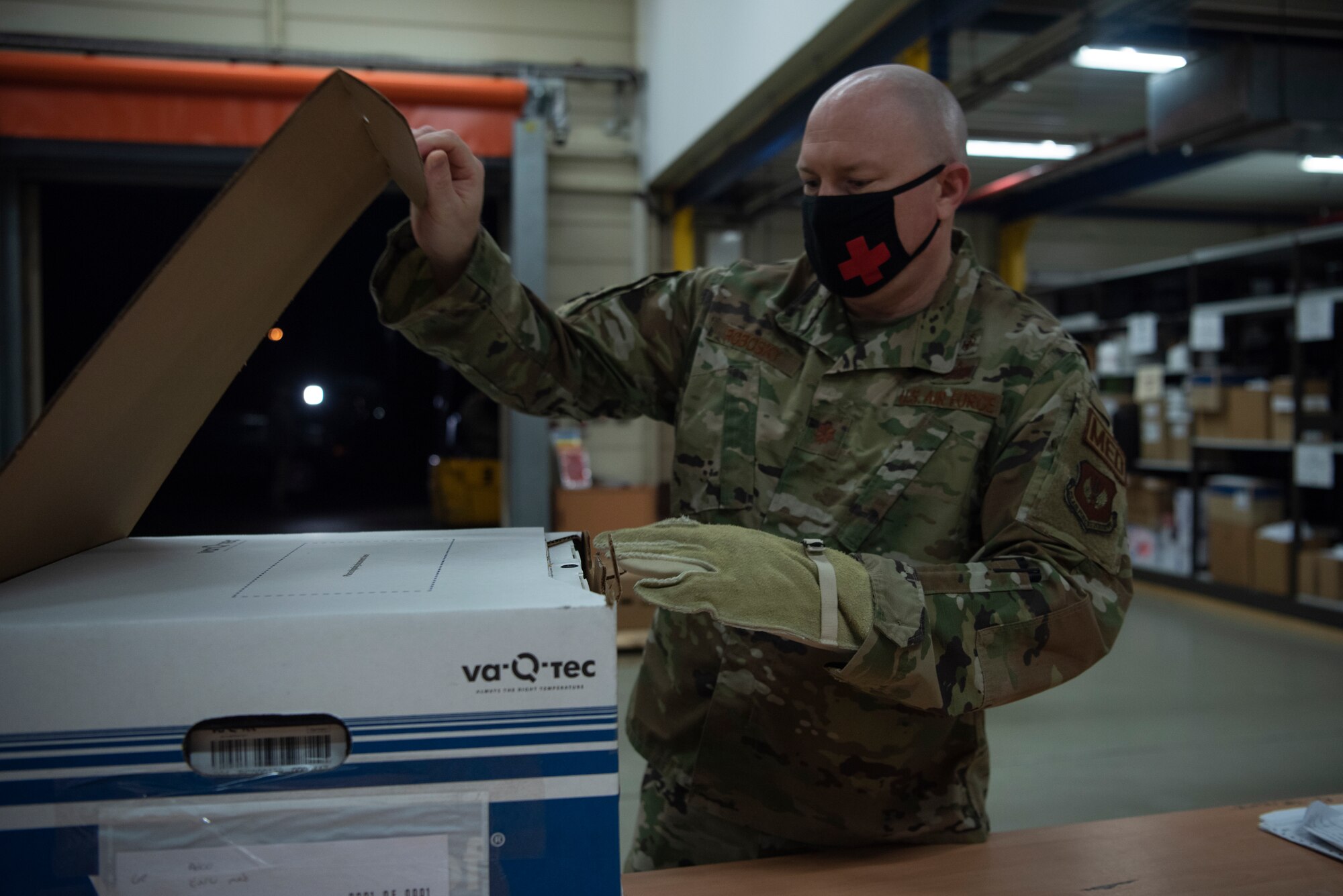 U.S. Air Force Maj. Christopher Robosky, 86th Medical Group medical logistics flight commander, opens a box containing COVID-19 vaccinations at Ramstein Air Base, Germany, Dec. 30, 2020.
