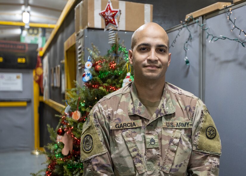 New York Police Officer and U.S. Army Staff Sgt. Samuel Garcia, intelligence analyst noncommissioned officer, 719th Movement Control Battalion, poses for a photo after a special holiday call from New York City Police Commissioner Dermot Shea at Camp Arifjan, Kuwait, Dec 23, 2020. During the call Shea thanked Garcia for his continued service to the nation as he serves his country in support of Operation Spartan Shield.